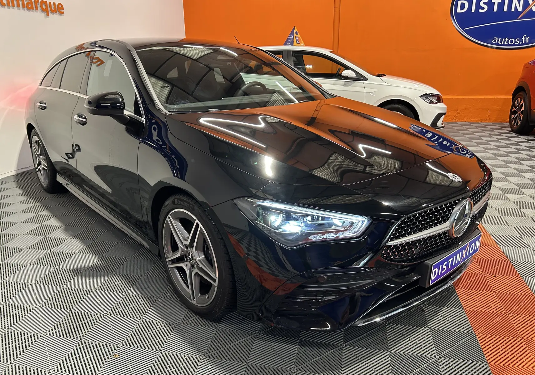 Mercedes Classe CLA Shooting Brake II 200D AMG noir métallisé vue 3/4 avant droit avec phares LED allumés dans showroom.