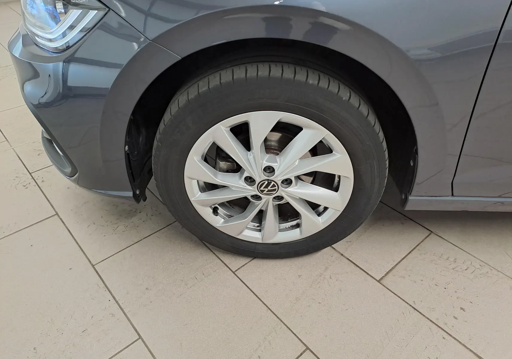 Gros plan sur la roue avant gauche d'une Volkswagen Polo gris cendré 2023, avec jante alliage et partie du pare-chocs visible.