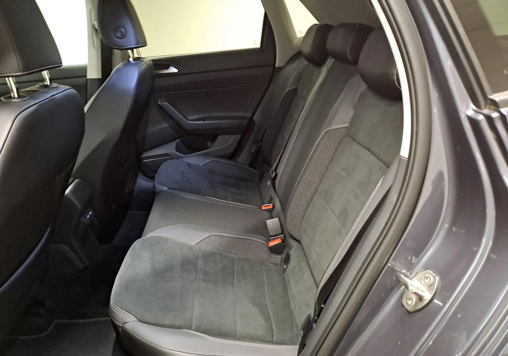 Vue intérieure côté droit des sièges arrière en tissu et cuir gris d'une Volkswagen Polo 2023 gris cendré avec vitres arrière surteintées.