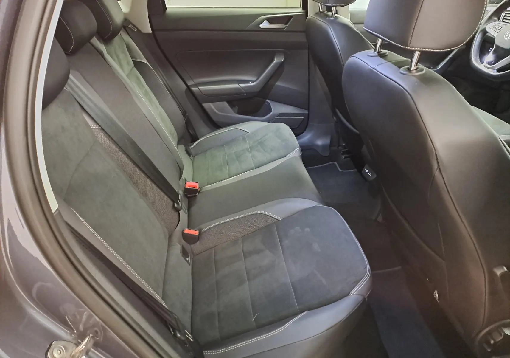 Vue intérieure côté gauche montrant les sièges arrière en tissu et cuir noir de la Volkswagen Polo gris cendré 2023.
