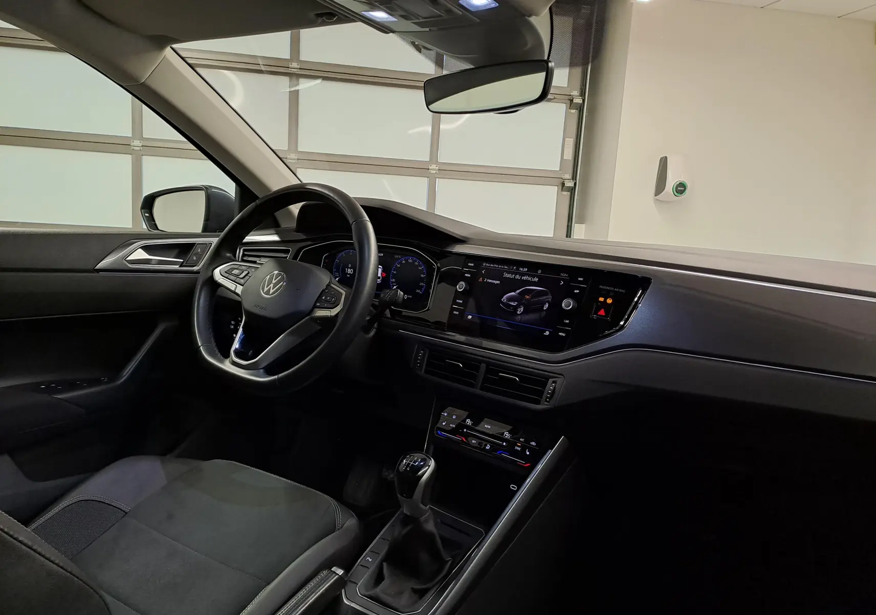 Vue intérieure côté conducteur de la Volkswagen Polo 2023 gris cendré, avec tableau de bord digital et boîte manuelle.