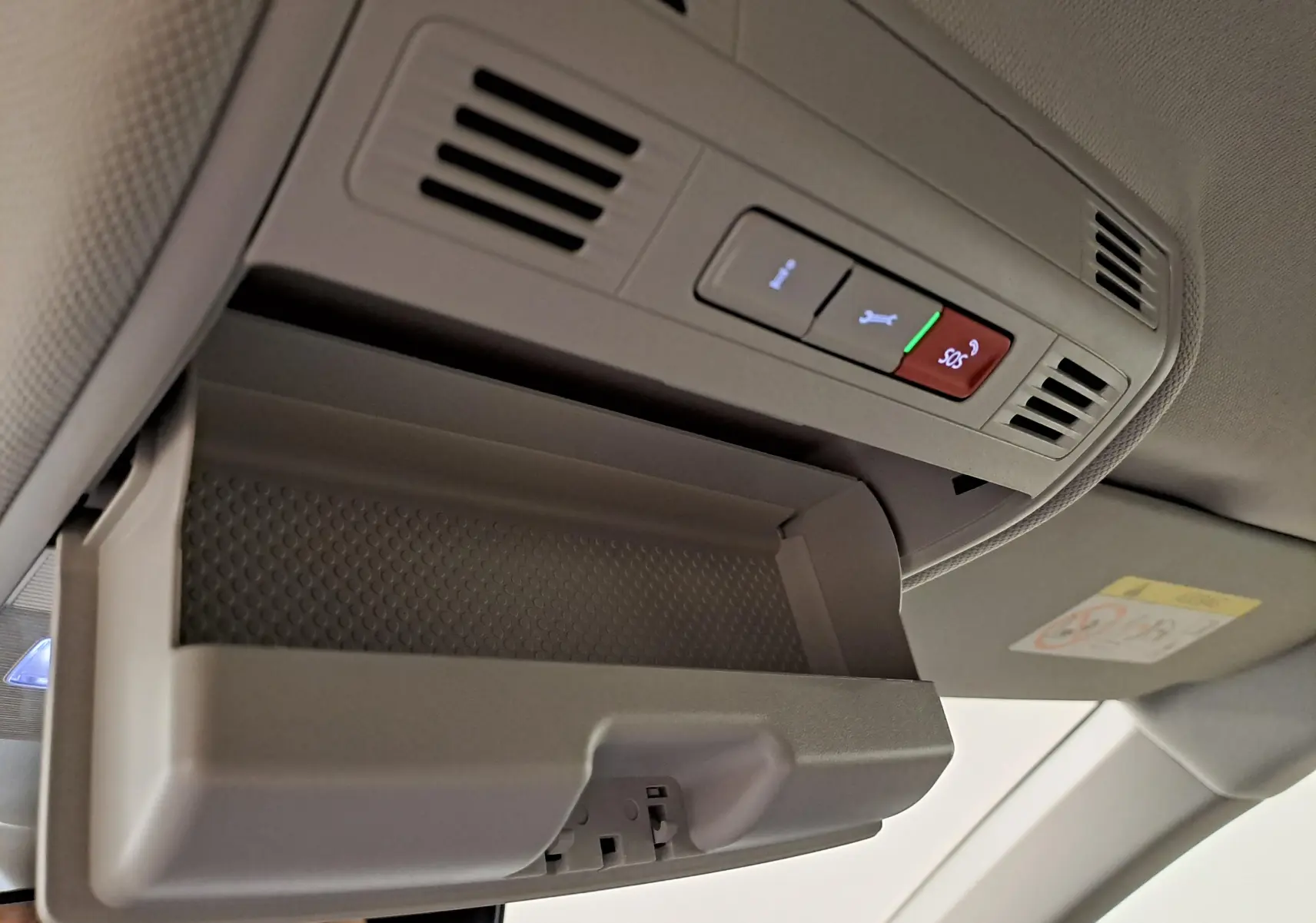 Gros plan sur le rangement lunettes ouvert et les commandes d’éclairage au plafond intérieur d’une Volkswagen Polo gris cendré 2023.