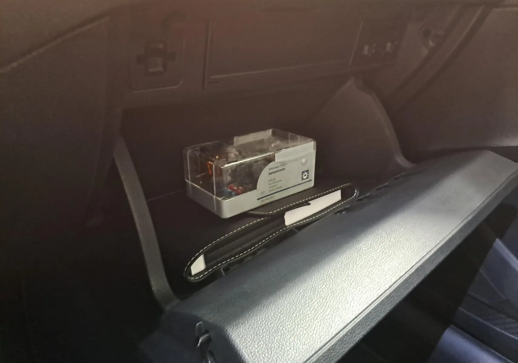 Gros plan sur la boîte à gants ouverte d'une Volkswagen Polo gris cendré 2023, avec un kit d'ampoules à l'intérieur.