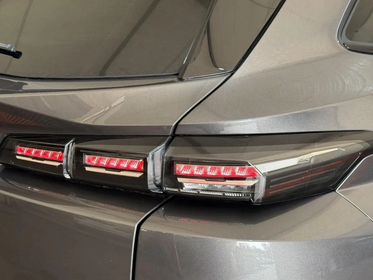 Gros plan sur les feux arrière rouges du côté gauche d’un Peugeot 308 SW gris foncé 2022.