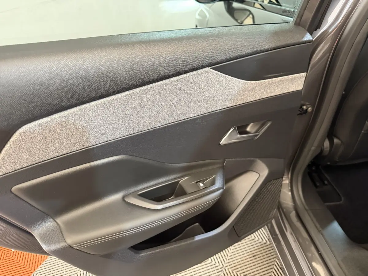 Vue rapprochée de la porte arrière droite gris foncé de la Peugeot 308 SW avec habillage noir et gris clair texturé.