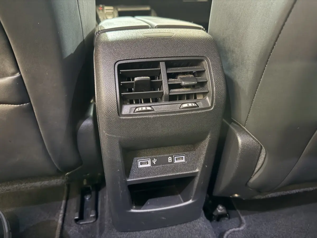 Vue rapprochée de la ventilation arrière et des ports USB intégrés entre les sièges noirs d’une Peugeot 308 SW gris foncé.