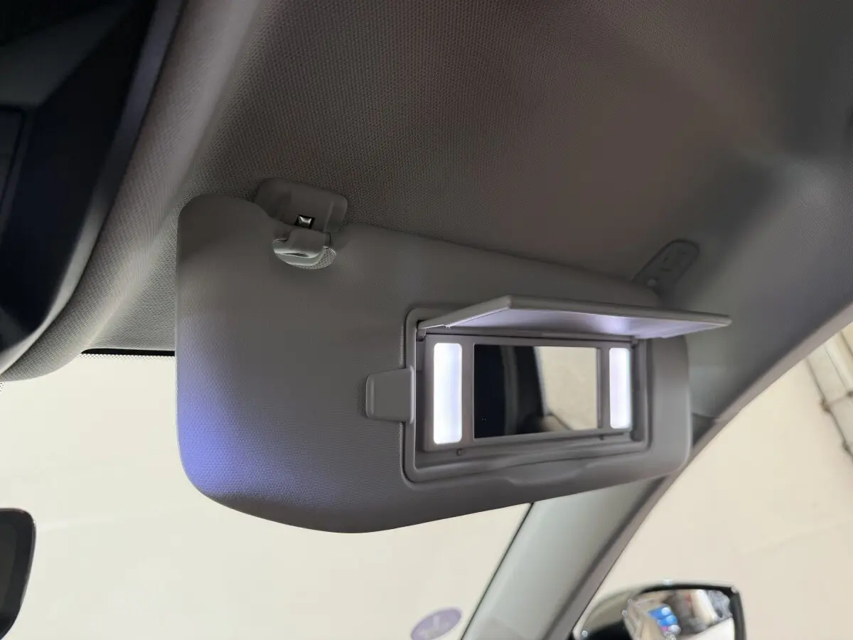 Détail du pare-soleil côté conducteur avec miroir éclairé dans l’habitacle gris clair d’une Peugeot 308 SW 2022.