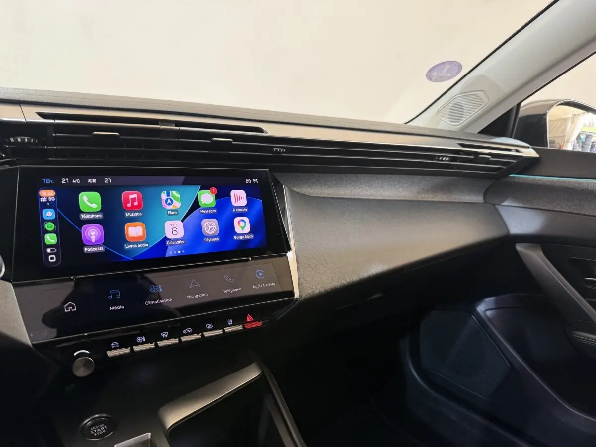 Vue intérieure côté passager du tableau de bord de la Peugeot 308 gris foncé avec écran tactile multimédia allumé.