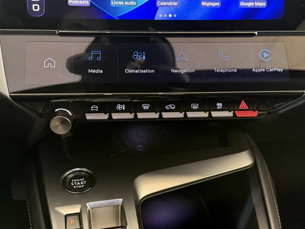Vue rapprochée de la console centrale de la Peugeot 308 gris foncé, avec écran tactile et boutons de commande éclairés.