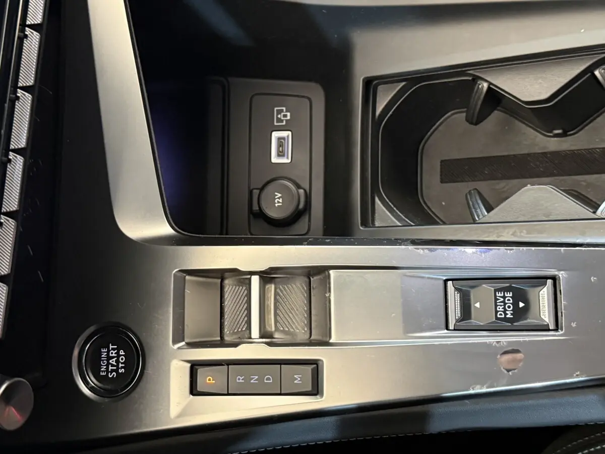 Vue rapprochée de la console centrale grise foncé de la Peugeot 308 avec boutons de boîte auto et bouton Drive Mode.