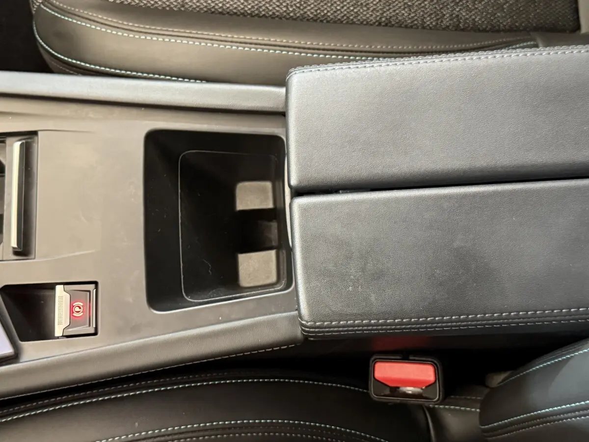 Vue rapprochée de la console centrale noire avec frein à main électrique et accoudoir en cuir de la Peugeot 308 gris foncé.