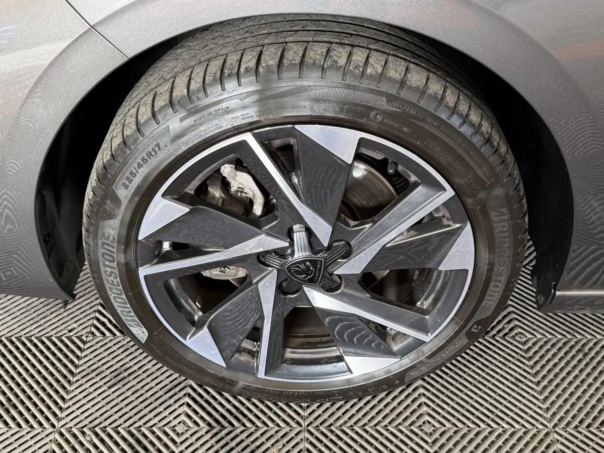 Gros plan sur la roue avant droite gris foncé d’une Peugeot 308 SW avec jante alliage au design géométrique.