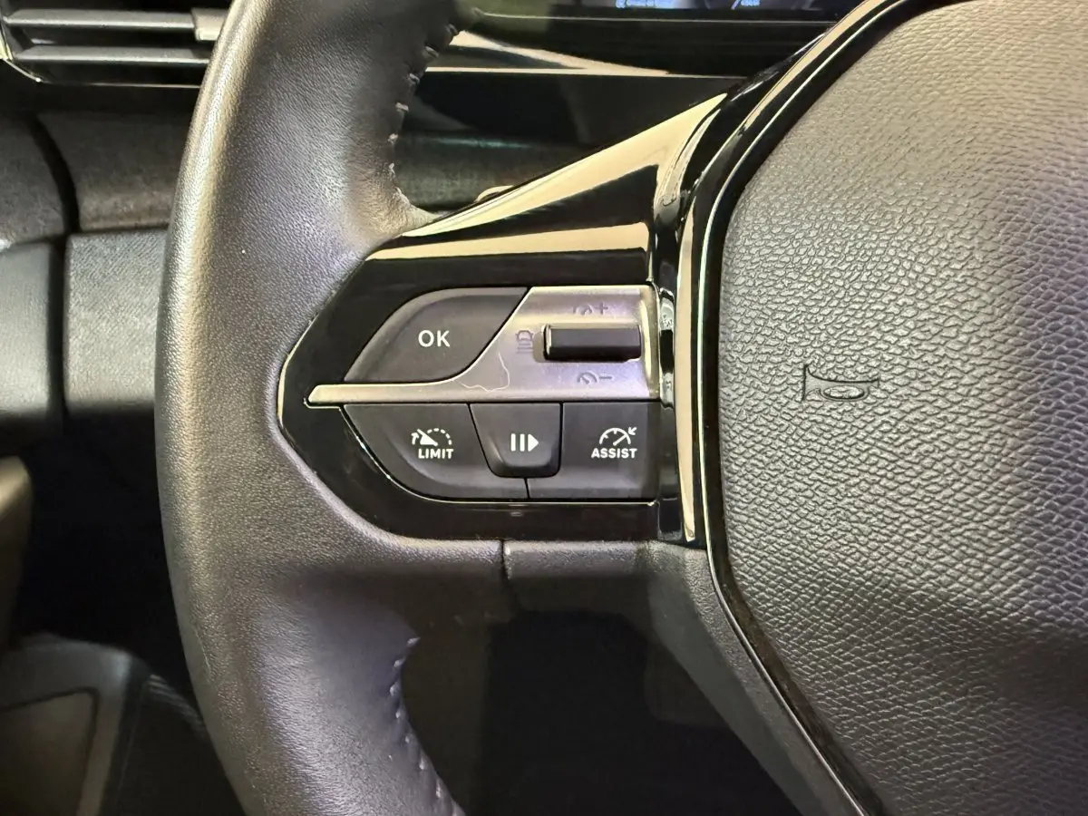 Gros plan sur les commandes de régulateur de vitesse et assistance au volant cuir noir du Peugeot 308 gris foncé 2022.