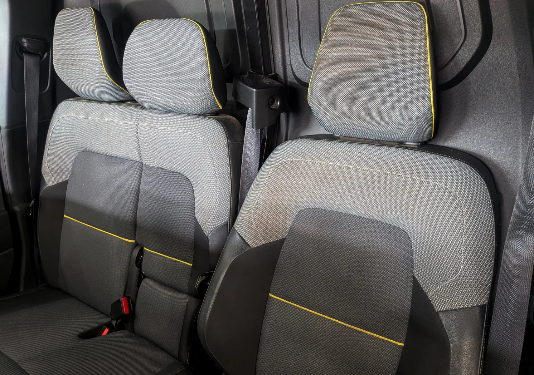 Vue rapprochée des sièges avant en tissu gris avec surpiqûres jaunes du Renault Kangoo Van 2021 blanc minéral.