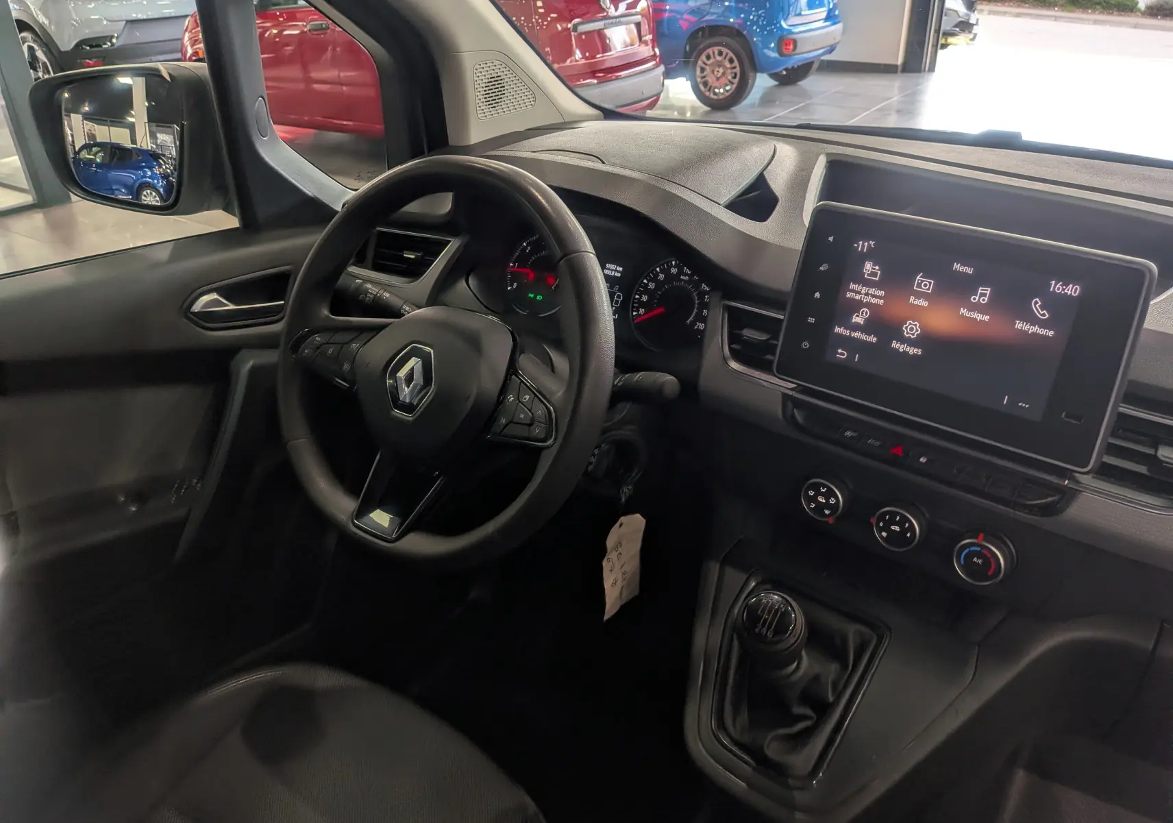 Vue intérieure côté conducteur du Renault Kangoo 2021, tableau de bord noir avec écran tactile et levier de vitesses manuel.