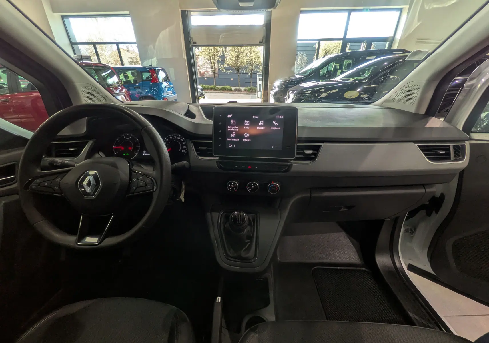 Vue intérieure avant du Renault Kangoo 2021 blanc, tableau de bord avec écran tactile et volant multifonction.