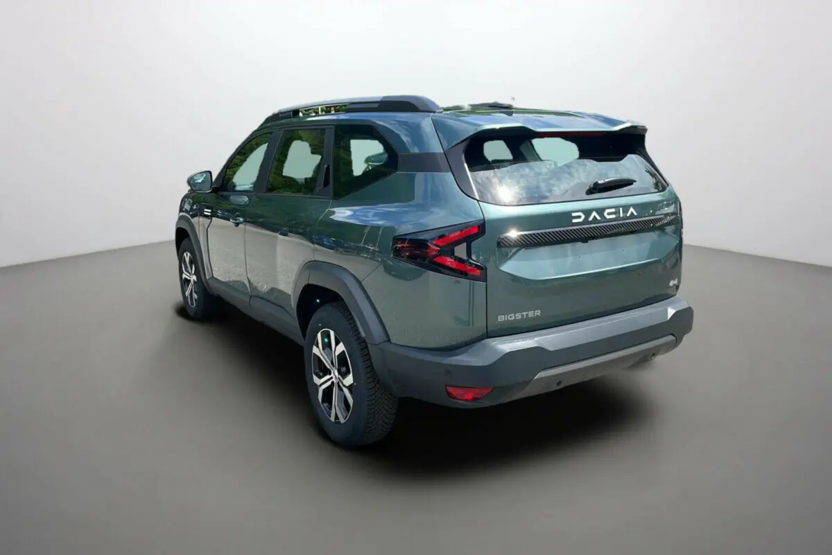 Vue 3/4 arrière droite du Dacia Bigster vert cèdre avec barres de toit et jantes alu 17 pouces visibles.