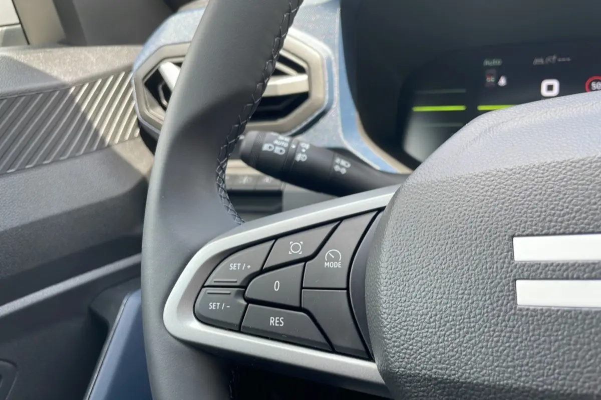 Gros plan sur le volant cuir du Dacia Bigster vert cèdre, mettant en valeur les commandes de régulateur de vitesse côté gauche.