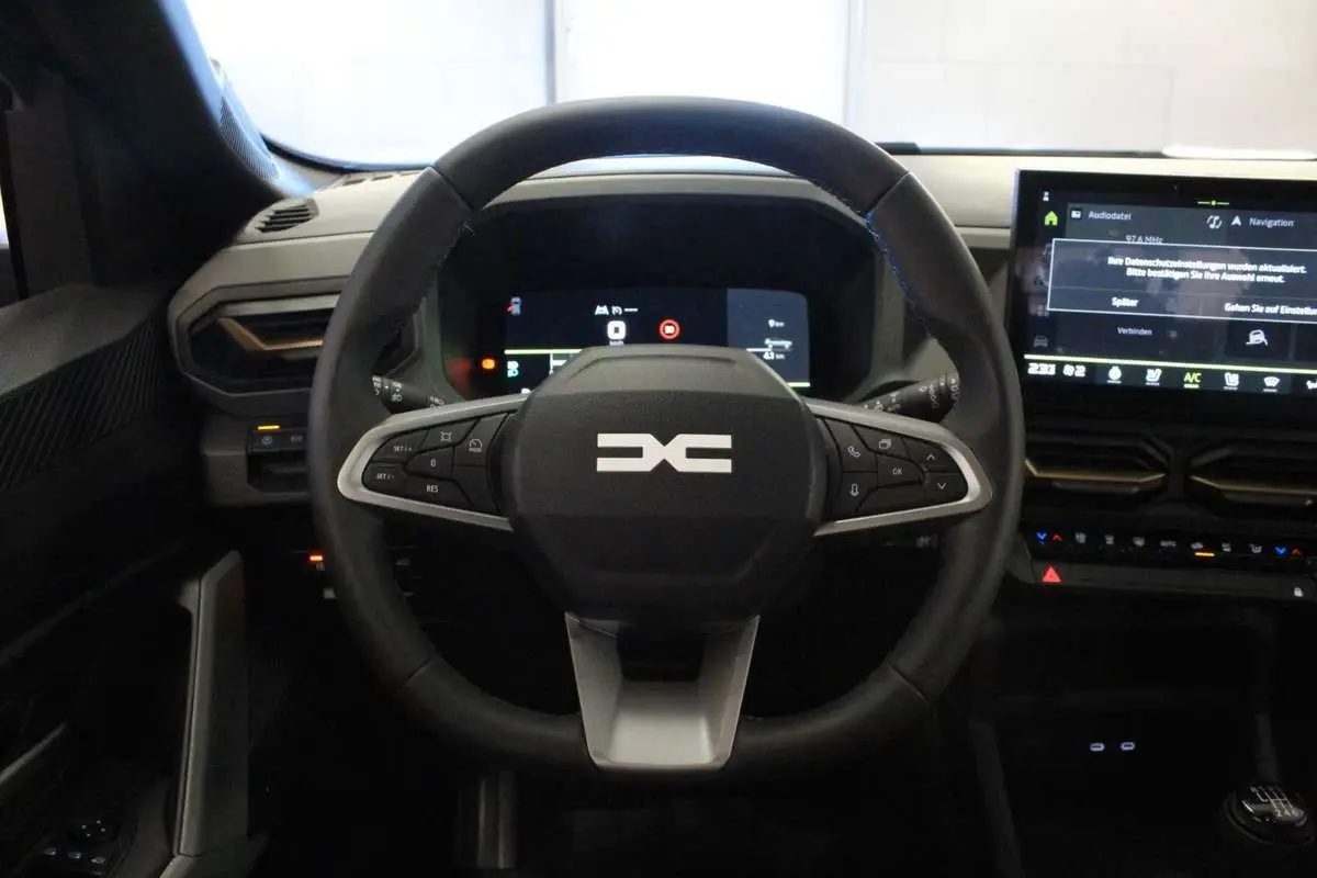 Vue frontale du volant cuir noir du Dacia Bigster 2026 avec tableau de bord digital et écran tactile central.