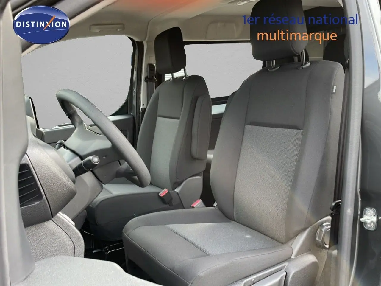 Vue intérieure côté conducteur du Citroën Jumpy Cabine Approfondie gris titane, sièges en tissu gris et volant multifonction.