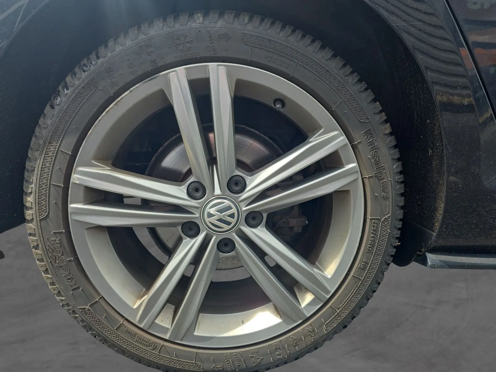 Gros plan sur la roue avant droite d'une Volkswagen Golf noire 2019, jante alliage R-line à 5 doubles branches.
