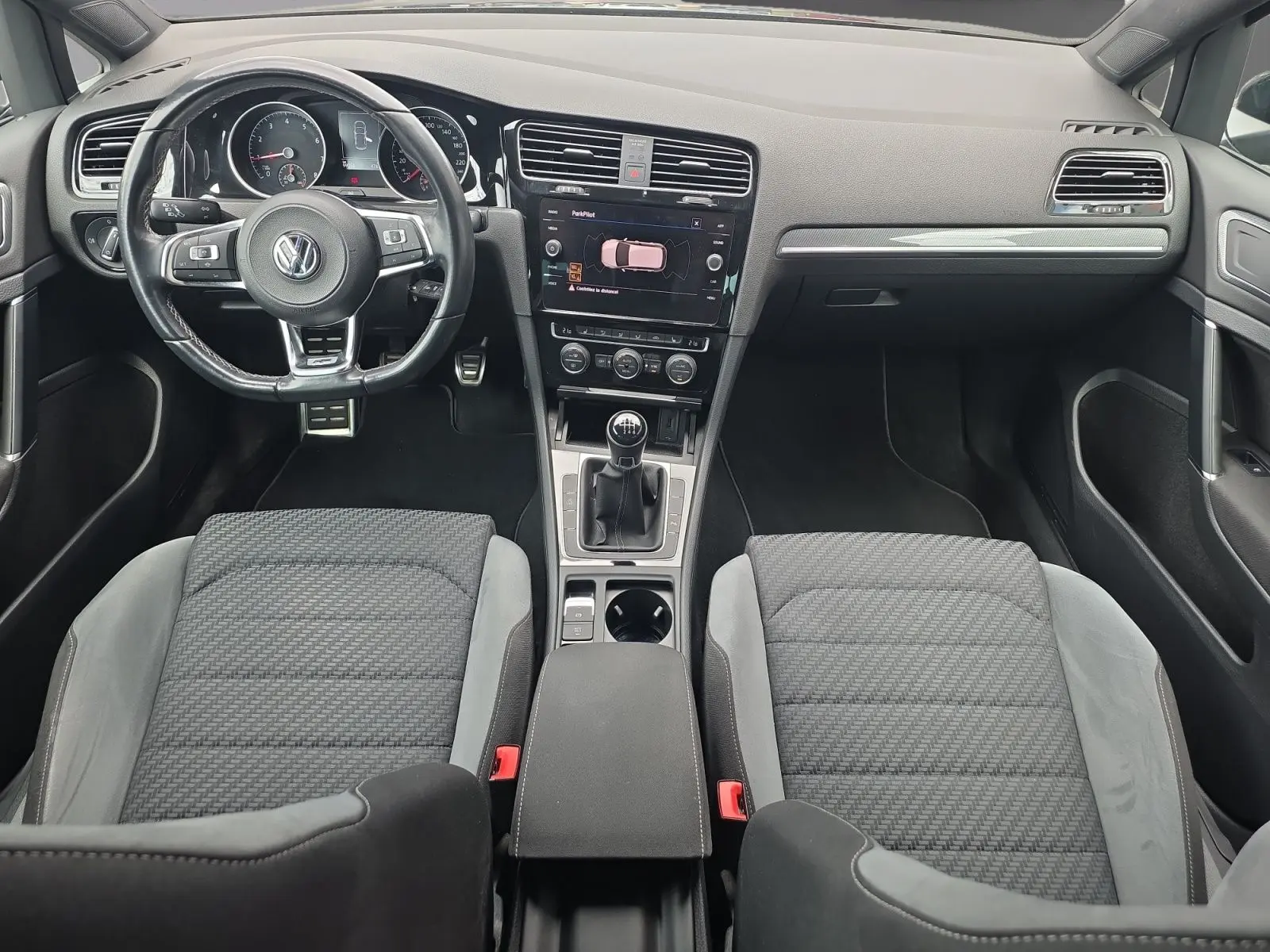 Vue intérieure avant de la Volkswagen Golf 1.5 TSI EVO 150 R-line noire de 2019 avec volant multifonction et boîte manuelle.