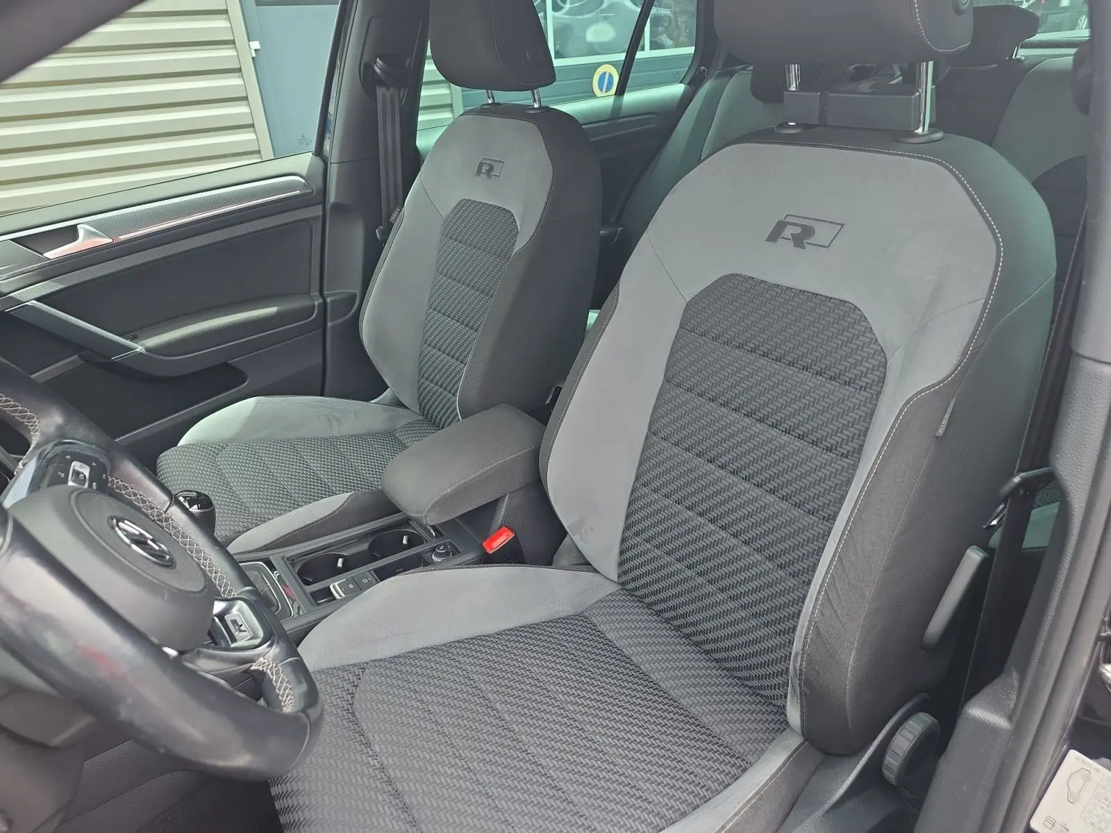 Vue intérieure rapprochée des sièges avant gris avec logo R de la Volkswagen Golf 1.5 TSI EVO 150 R-line noire de 2019.