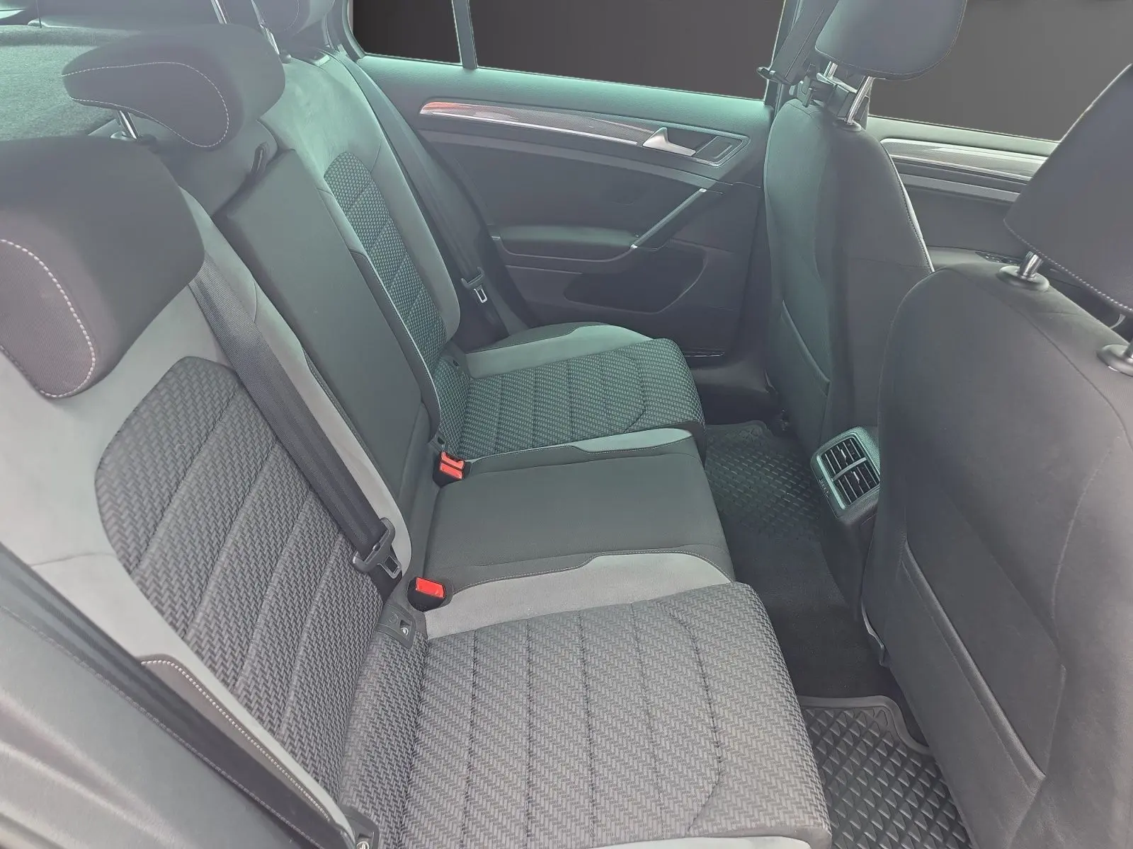 Vue intérieure côté arrière droit montrant les sièges arrière en tissu gris avec surpiqûres blanches d’une Volkswagen Golf 1.5 TSI EVO 2019.