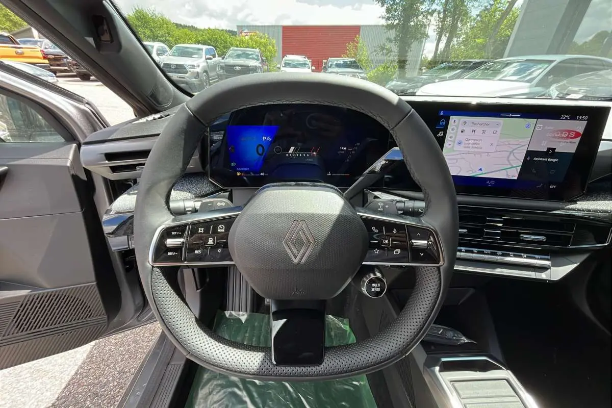 Vue intérieure centrée sur le volant multifonctions et l'écran tactile de la Renault Clio gris schiste 2026.