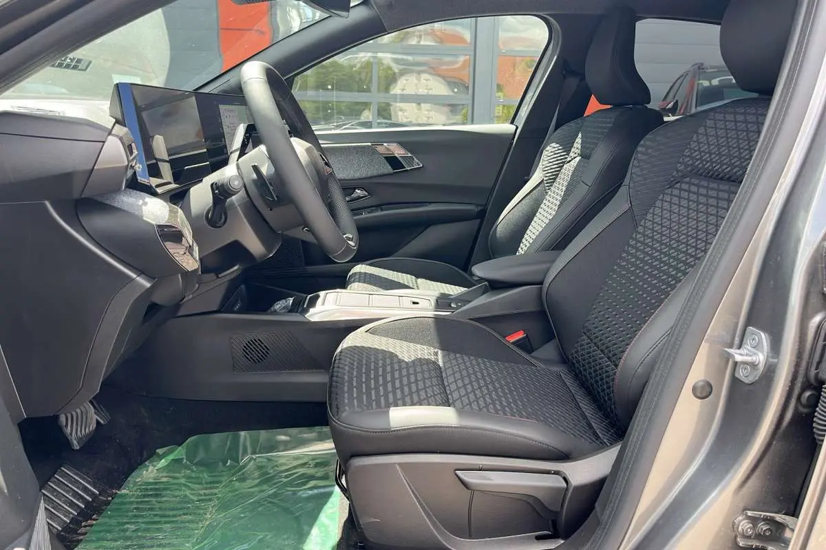 Vue intérieure côté conducteur de la Renault Clio gris schiste 2026, sièges tissu à motifs et tableau de bord moderne.