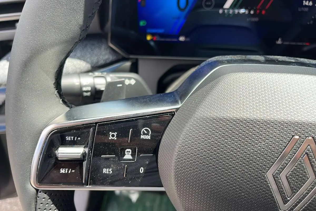 Gros plan sur le volant multifonctions noir de la Renault Clio 6 TCE 115 EDC Techno avec commandes de régulateur.