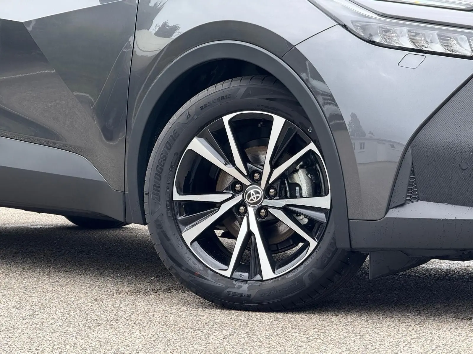 Gros plan sur la roue avant droite du Toyota C-HR gris atlas 2025, mettant en valeur la jante alliage noire et argent.