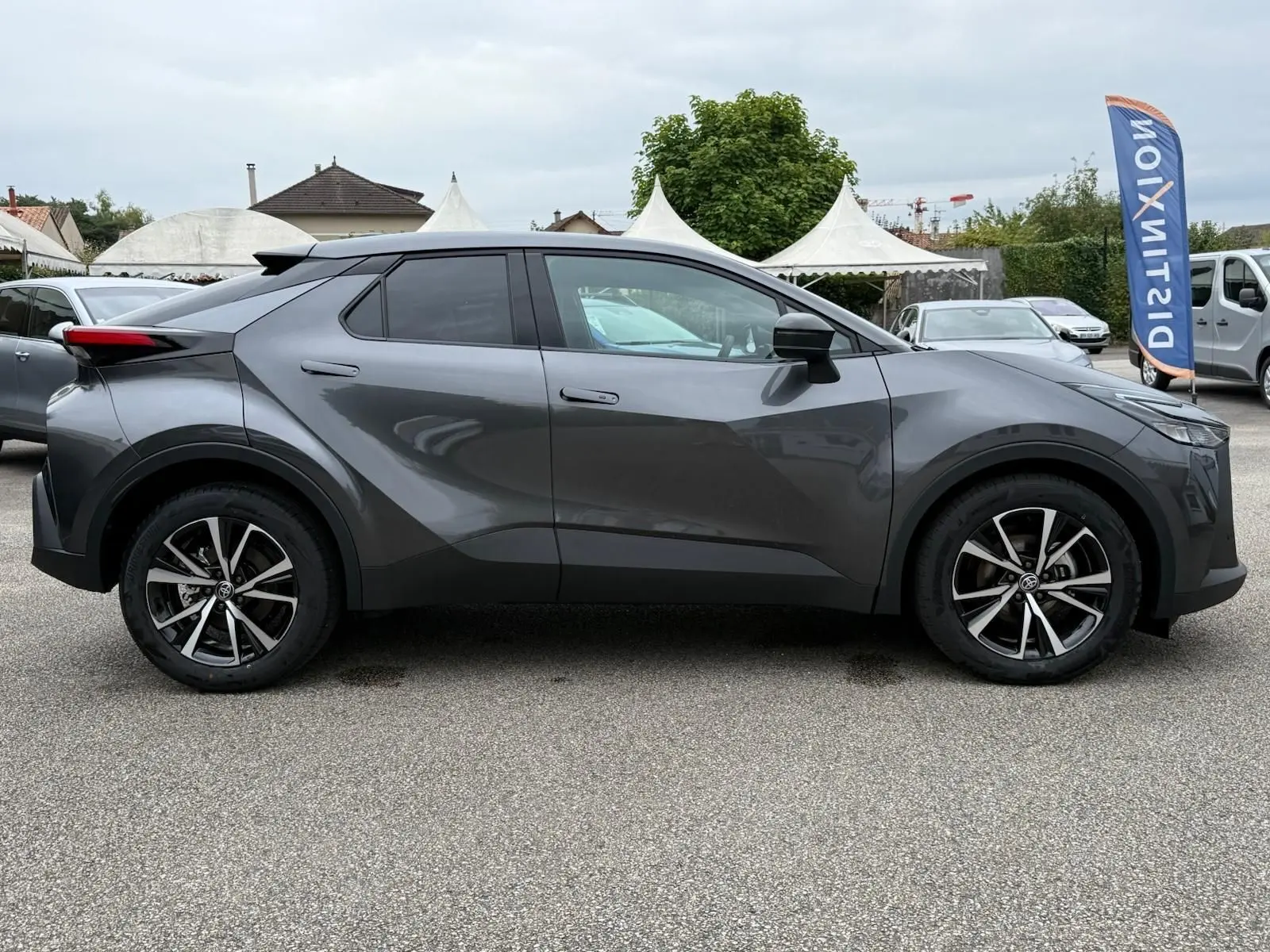 Profil côté gauche du Toyota C-HR 1.8 140CH STYLE 2025 en gris atlas avec jantes alliage et lignes anguleuses marquées.