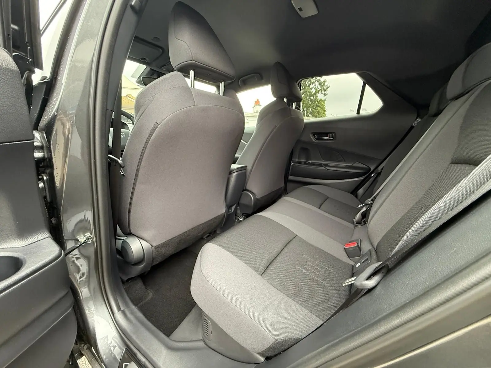 Vue intérieure arrière côté gauche du Toyota C-HR 1.8 140CH STYLE gris atlas, sièges tissu bicolore gris et noir.