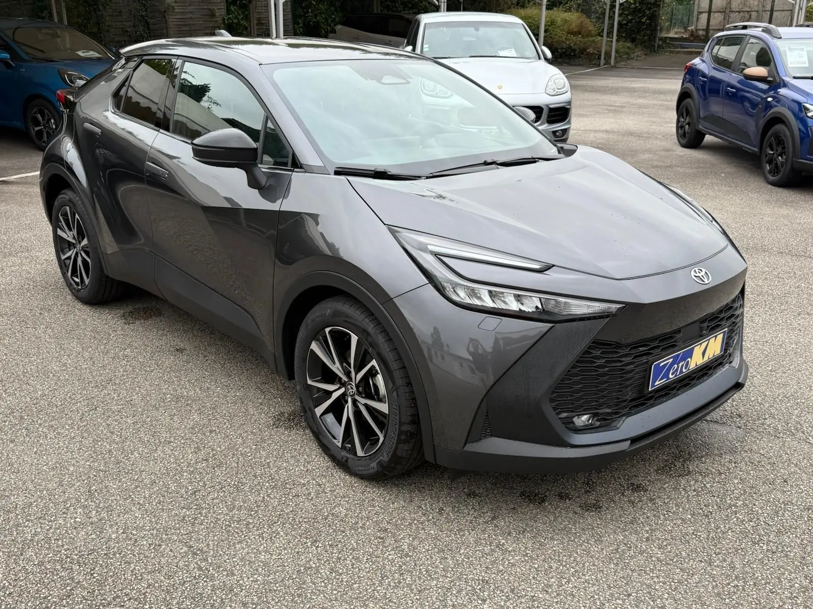 Toyota C-HR 1.8 140CH STYLE gris atlas en vue 3/4 avant droit, avec calandre noire et jantes alliage noires.