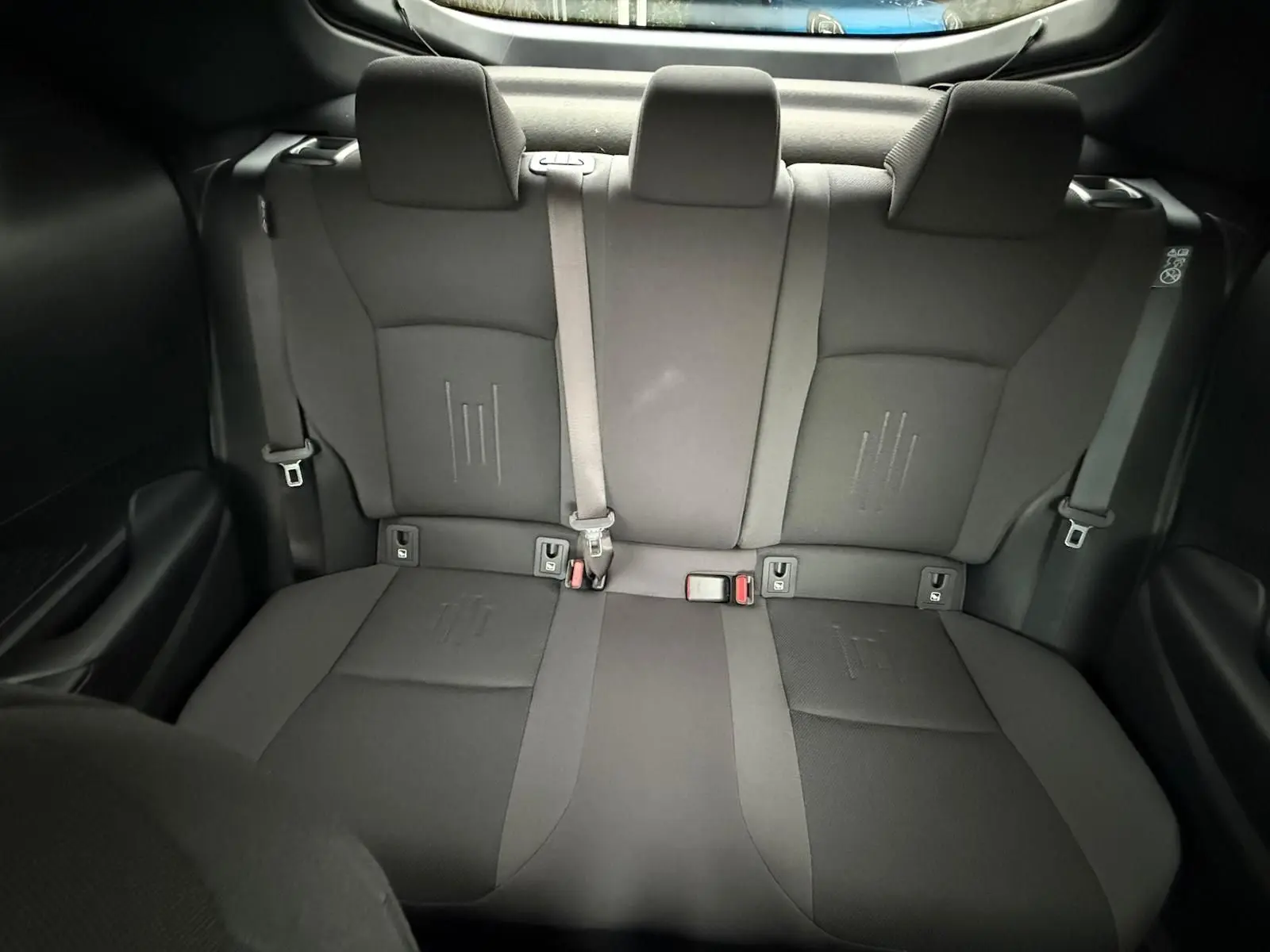 Vue arrière intérieure des sièges arrière noirs du Toyota C-HR 1.8 140CH STYLE MY25, tissus et ceintures visibles.