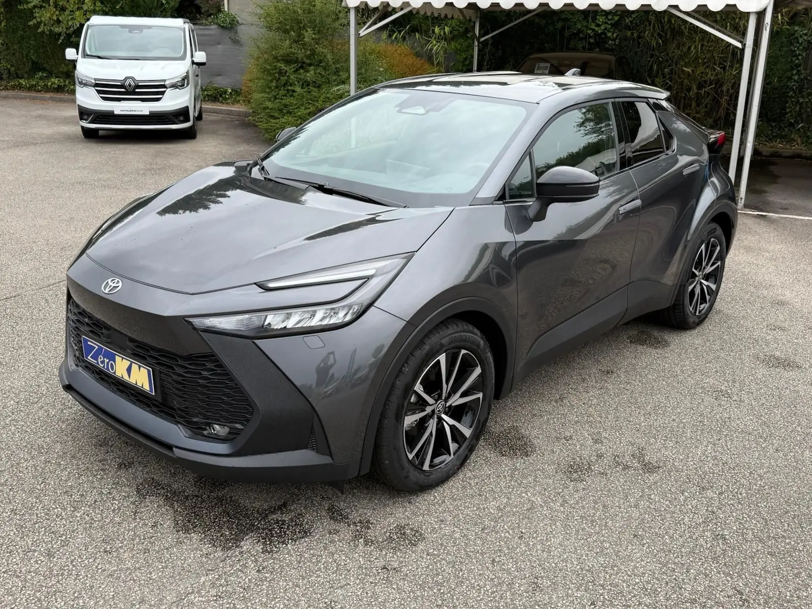Toyota C-HR 1.8 140CH STYLE gris atlas en 3/4 avant droit avec jantes noires et toit panoramique.