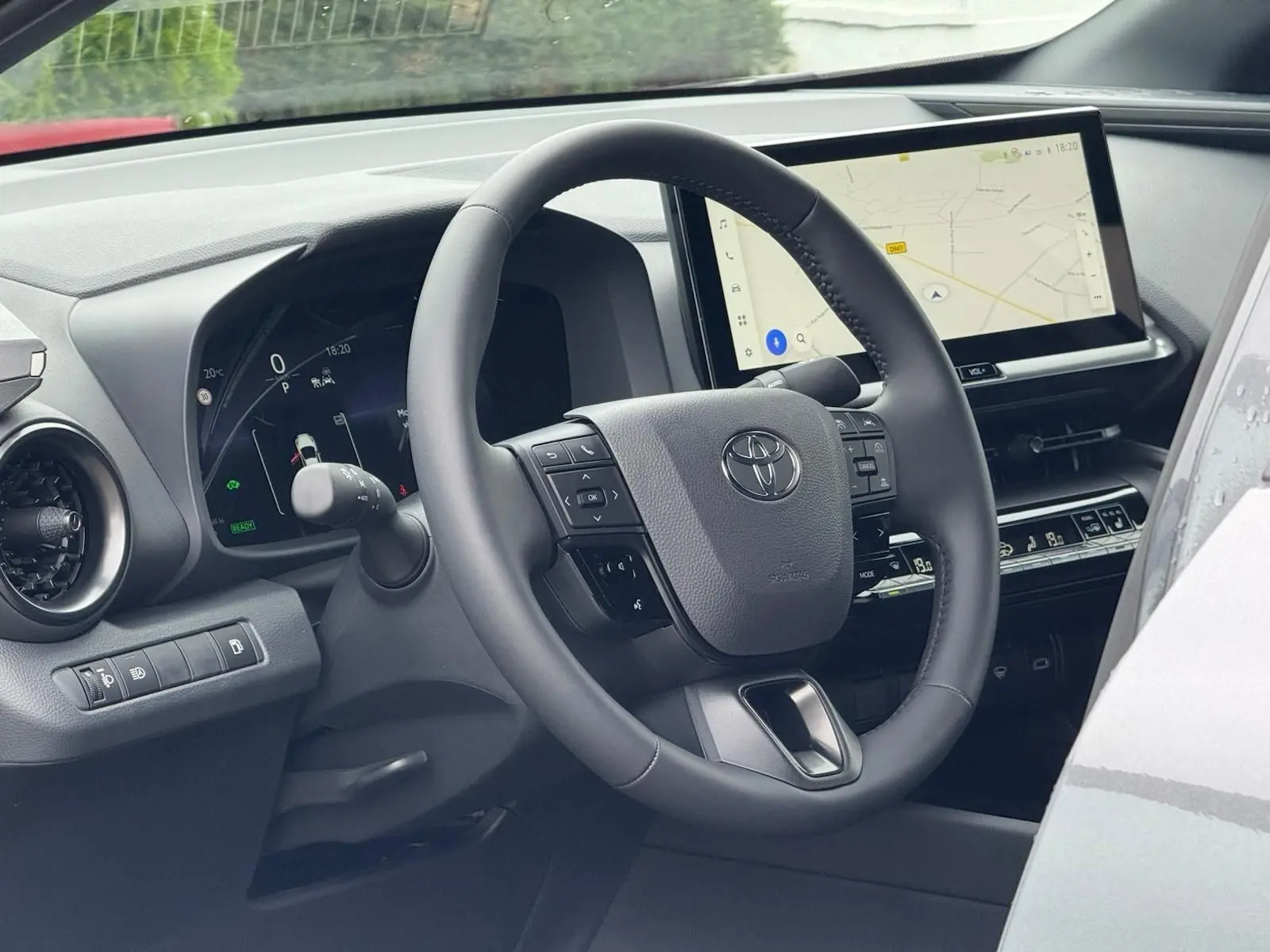 Vue intérieure du tableau de bord du Toyota C-HR gris atlas 2025, avec volant multifonction et écran tactile GPS.