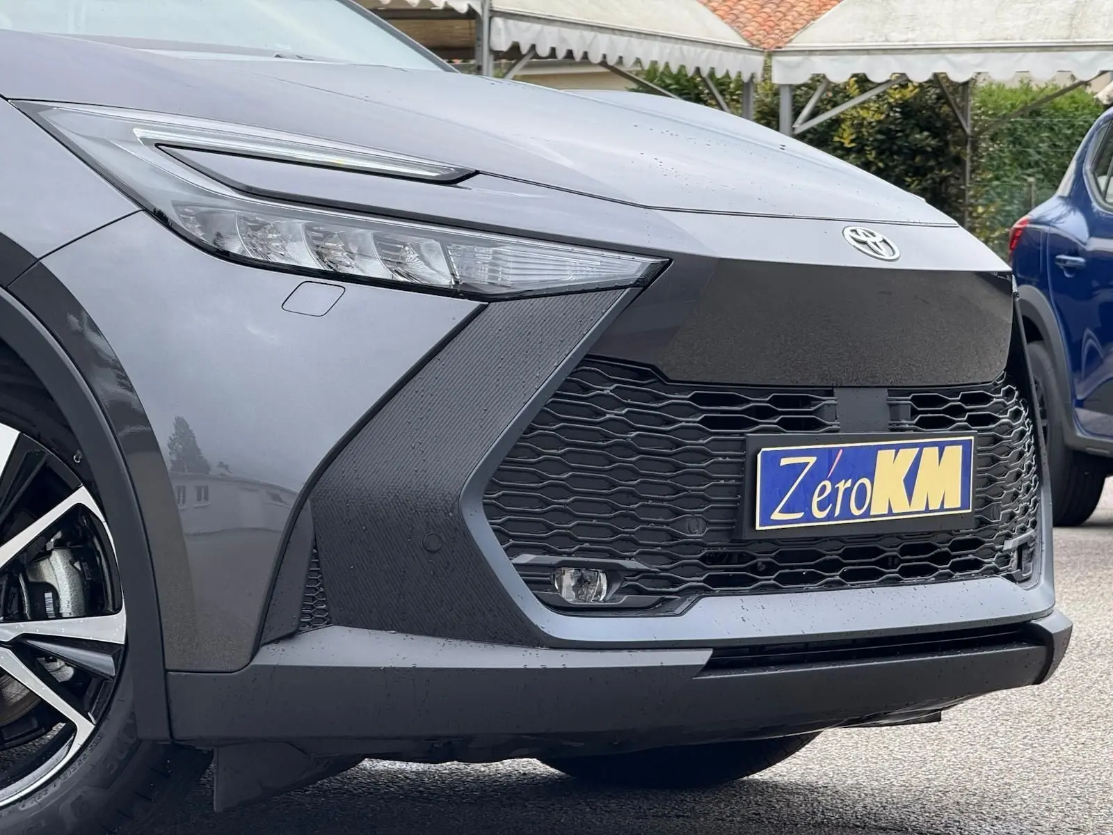 Vue rapprochée 3/4 avant gauche du Toyota C-HR 1.8 140CH STYLE gris atlas avec calandre noire et phares LED fins.