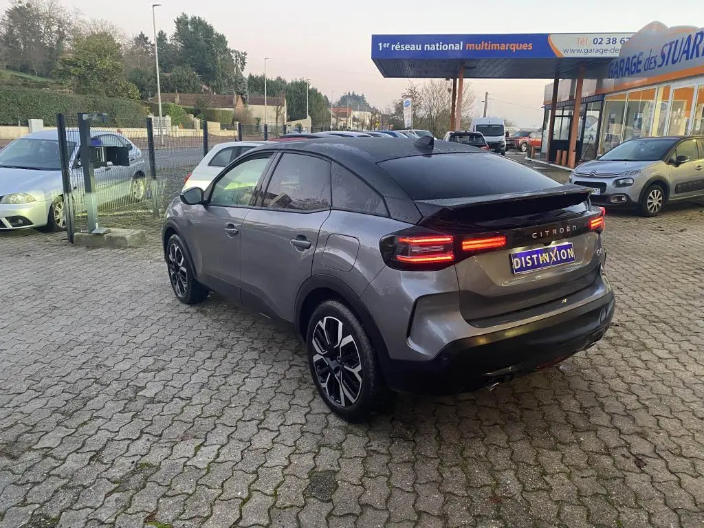 Vue 3/4 arrière droite d'une Citroën C4 gris foncé avec toit noir, feux arrière LED et jantes alliage distinctives.