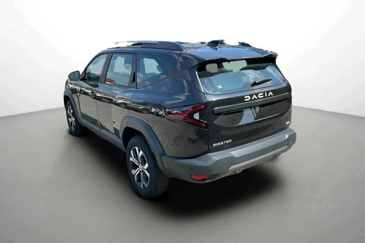 Vue 3/4 arrière droite du Dacia Bigster noir perle avec barres de toit et jantes alu 17 pouces visibles.