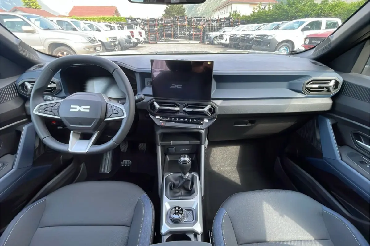 Vue intérieure avant du Dacia Bigster noir perle, mettant en valeur le volant cuir, la console centrale et l'écran tactile.