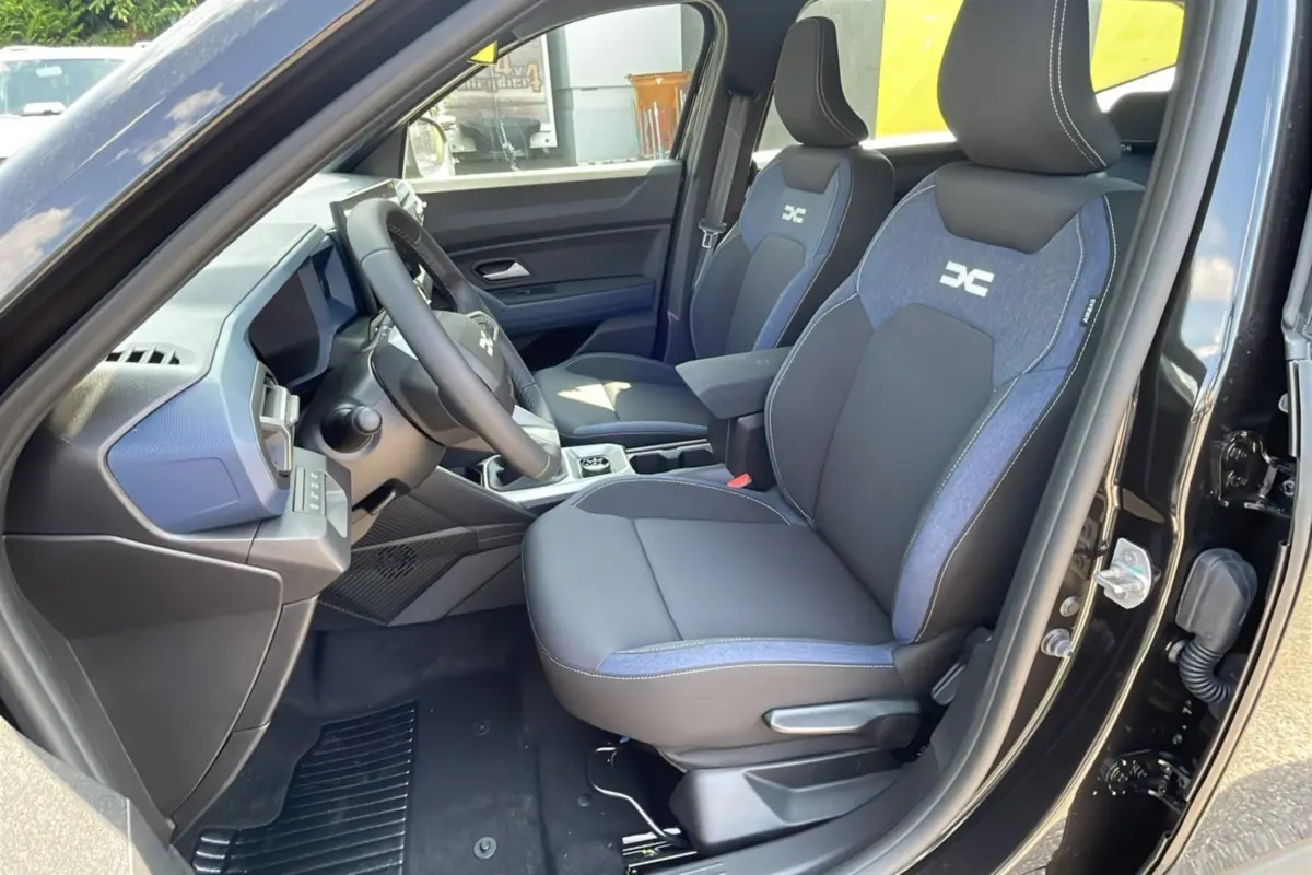 Vue intérieure côté conducteur du Dacia Bigster noir perle, sièges tissu noir et bleu avec logo DC brodé.