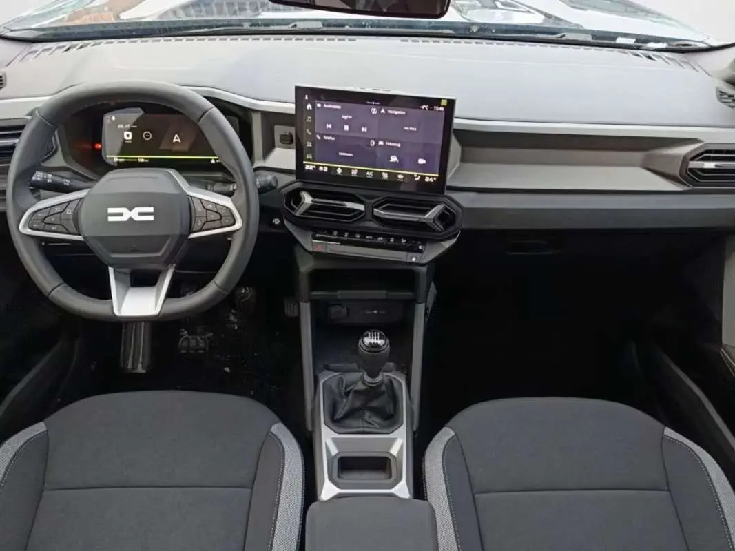 Vue intérieure frontale du tableau de bord et volant cuir noir du Dacia Bigster avec écran tactile central et boîte manuelle.