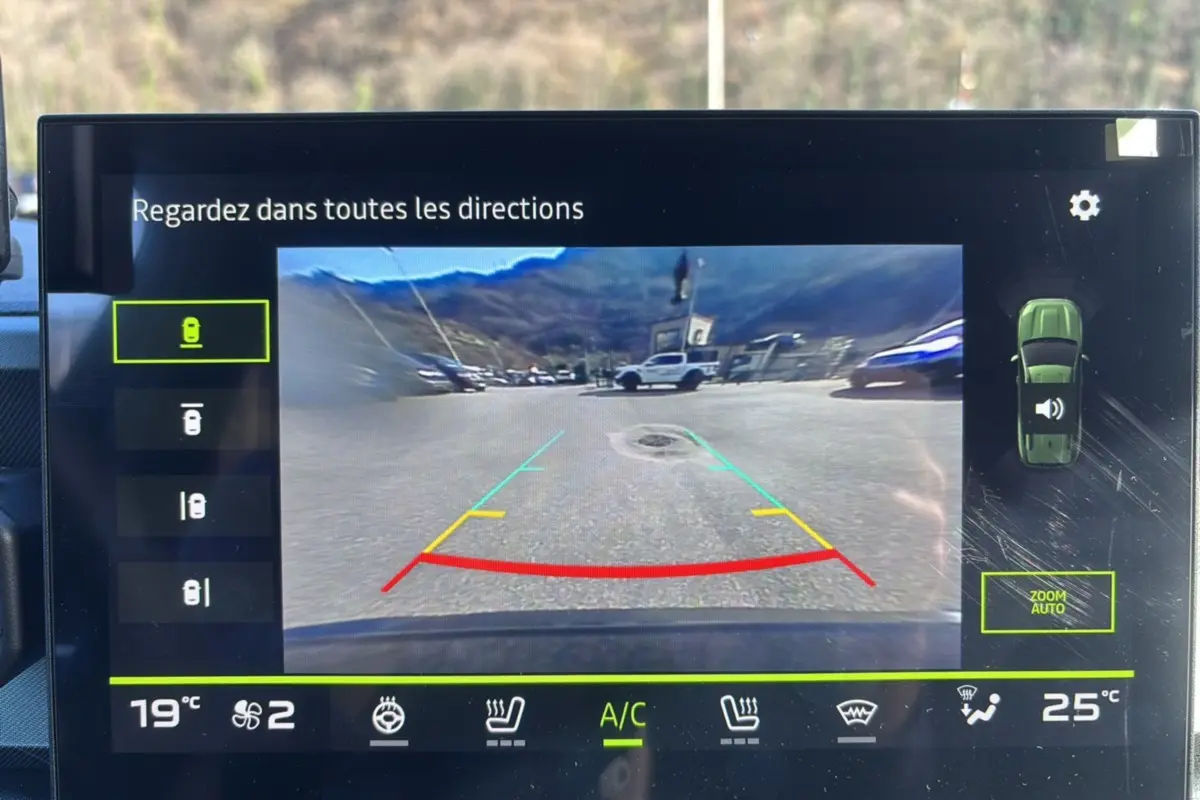 Écran multimédia montrant la caméra multiview arrière du Dacia Bigster bleu indigo avec lignes de guidage colorées.