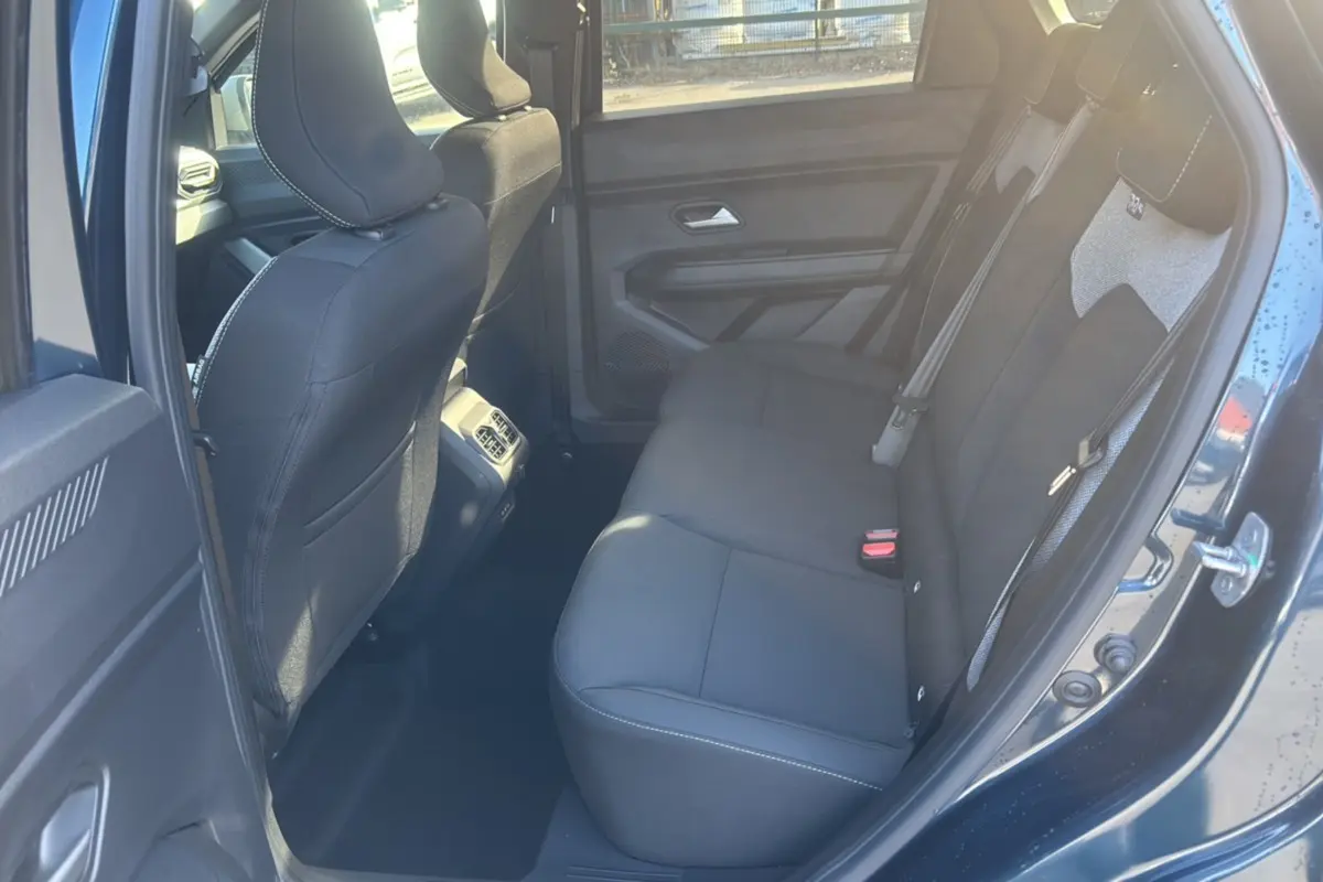 Vue intérieure arrière côté gauche du Dacia Bigster 2026 bleu indigo, montrant la banquette noire et les détails des sièges.