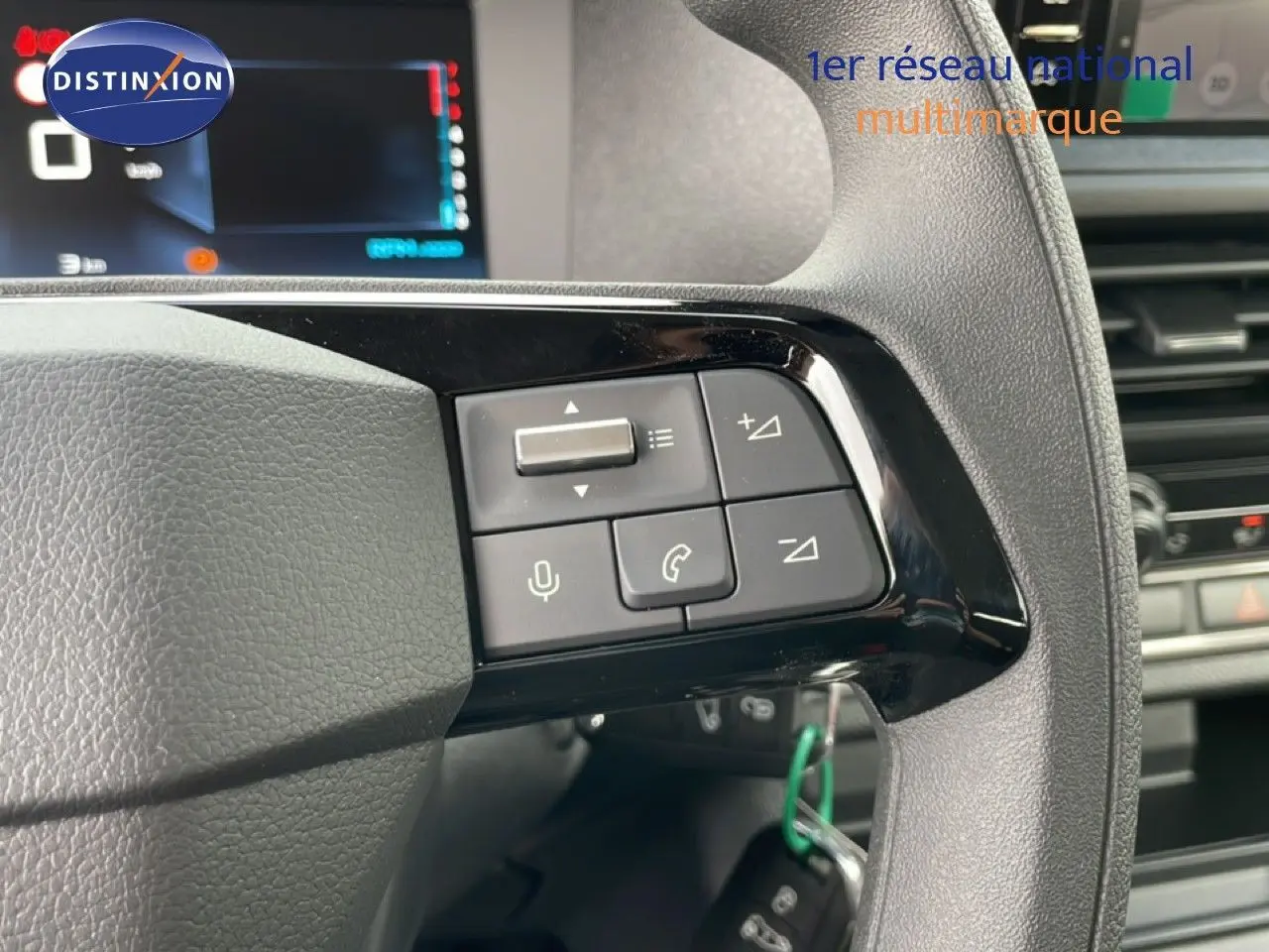 Gros plan sur les commandes au volant du Citroën Jumpy Cabine Approfondie gris titane, avec écran numérique en arrière-plan.