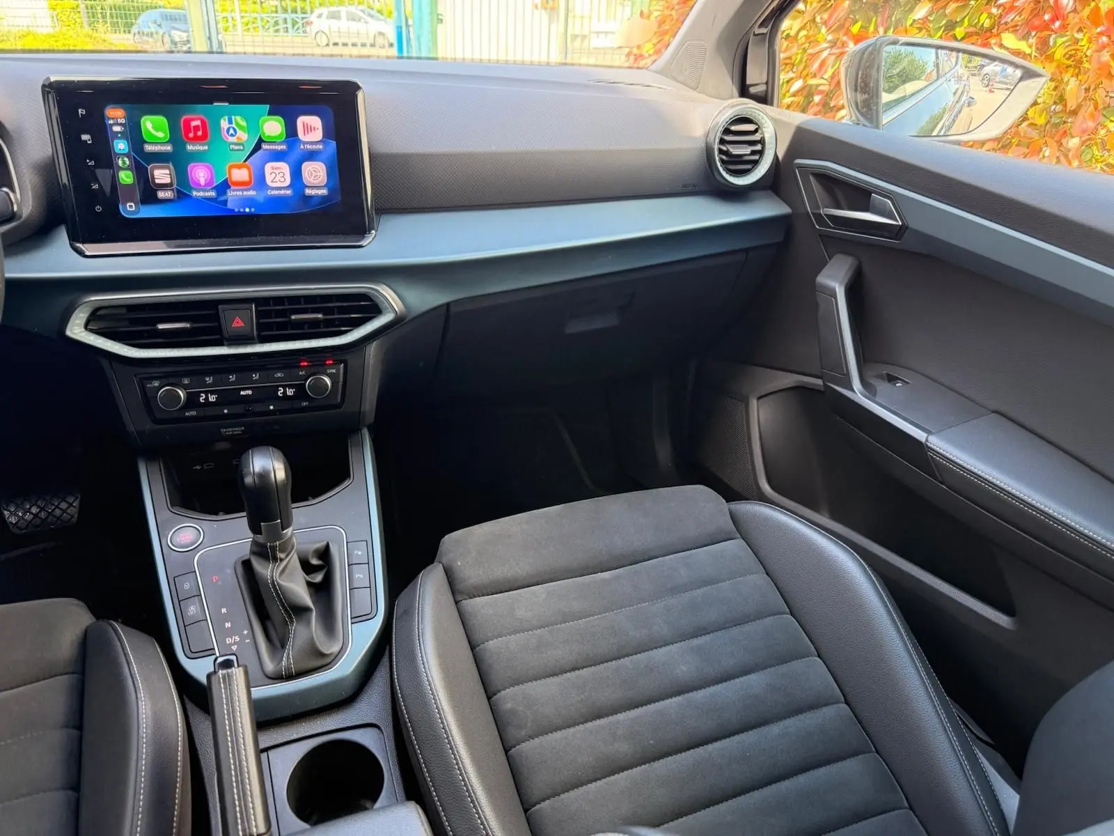 Vue intérieure côté passager du tableau de bord et console centrale noire du SEAT Arona 2022 avec écran tactile et sellerie mixte.
