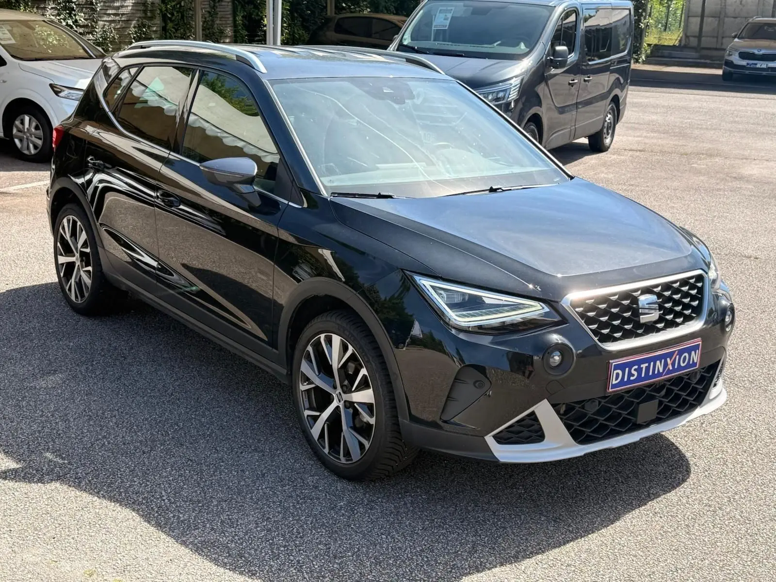 Vue 3/4 avant droite d'une SEAT Arona noire avec jantes alliage et calandre distinctive, stationnée en extérieur.