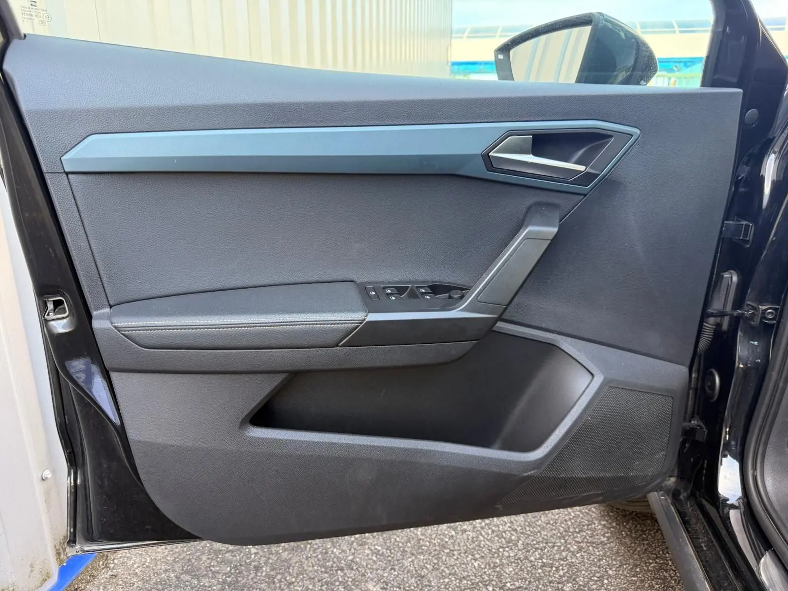 Vue intérieure de la porte avant gauche noire du SEAT Arona 2022 avec commandes de vitres et poignée argentée.